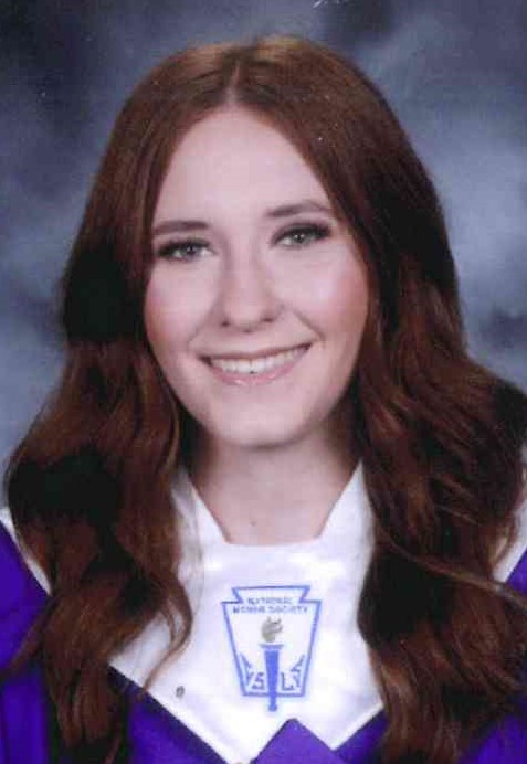 Photo of a young lady wearing graduation robes looking into the camera